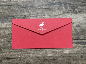 Détail en gros plan d'une enveloppe rouge avec motif flamant rose et texte imprimé.
