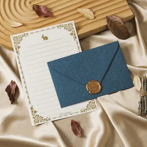 Vintage stationery set with dark blue envelope, gold-stamped letter paper, and wax seal.
