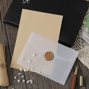 Detailopname van een doorschijnende pergamijn envelop en briefpapier plat op houten bureau.