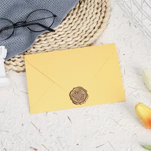 Detailed view of the elegant yellow envelope set with a vintage wax seal and decorative props.