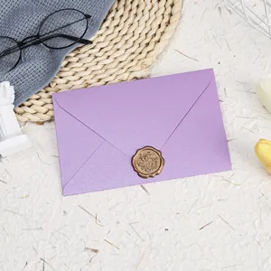 Detail view of a elegant light purple pearlescent envelope with a golden wax seal.