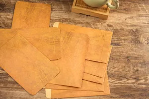 Close-up detail of vintage kraft paper envelopes scattered on rustic wooden desk background.