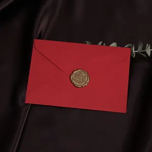 Rode linnen-getextureerde enveloppe met gouden waxzegel, elegant voor huwelijksuitnodigingen.