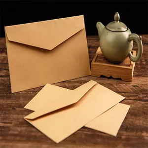 Vue détaillée d'enveloppes en kraft rétro sur table en bois avec accessoire théière