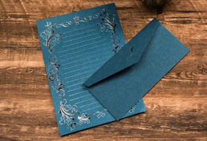 Detailed close-up of dark blue stationery letter paper and envelope set with metallic floral design.