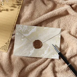 Vue de détail de l'enveloppe élégante en marbre doré avec sceau de cire et papier de papeterie.