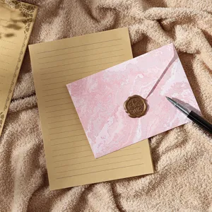 Ensemble de papeterie vintage avec papier kraft, enveloppe marbre rose et sceau pour lettres.