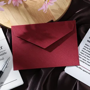 Close-up view of a dark red textured paper envelope on brown satin fabric background.