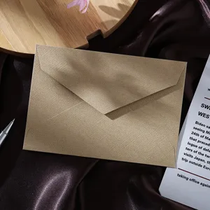 Close-up of a retro linen texture envelope on dark silk fabric with styling props.