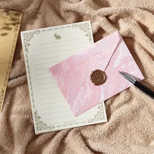 Vue detaillee d'un ensemble de papeterie vintage avec papier dore et sceau en cire rose.