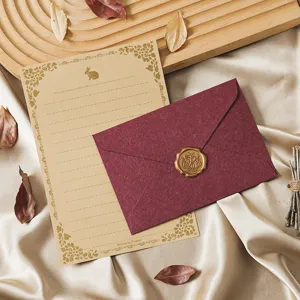 Vintage stationery set with kraft paper letter, burgundy envelope and elegant gold wax seal.