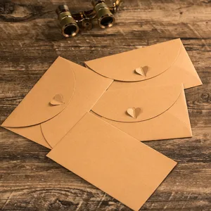Close up of vintage kraft paper envelopes with cute heart clasps on rustic wooden table.