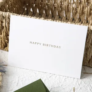 Elegante biglietto di auguri bianco con testo dorato per feste di compleanno.