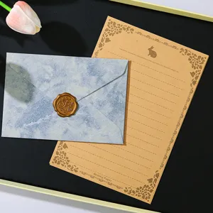 Set di cancelleria retrò con busta blu marmorizzata, carta da lettere floreale e sigillo.