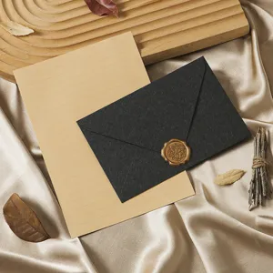 Close-up detail of vintage style stationery set featuring black envelope, wax seal, and kraft paper.