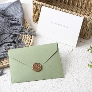 Set di biglietti d'auguri con busta verde avocado e sigillo in cera per benedizione di capodanno.