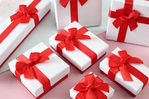 Detalle de cerca de varios tamaños de cajas de regalo blancas con elegantes lazos de cinta roja.
