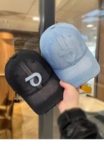 Vista dettagliata di berretti da baseball in denim delavé con logo ricamato, stile streetwear.