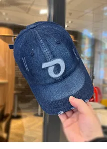 Primo piano del cappellino denim blu scuro con lettera P ricamata e visiera sfilacciata.
