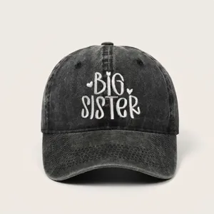 Detailweergave van gewassen denim baseballpet met Big Sister borduursel en maten.