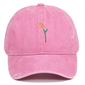 Gros plan d'une casquette de baseball en coton lavé rose avec une broderie de tulipe délicate