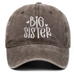 Detail van wit 'BIG SISTER' borduursel op een bruine vintage gewassen baseballpet