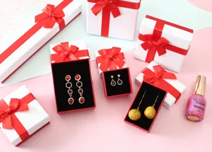 Vista detallada de cajas de regalo para joyas de cartón blanco con elegantes lazos rojos