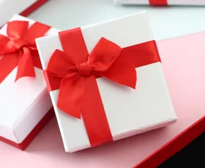 Primer plano de una elegante caja de regalo blanca adornada con un lazo rojo