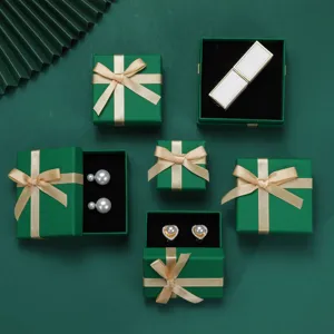 Dettaglio di eleganti scatole regalo per gioielli verde oceano con fiocchi champagne.