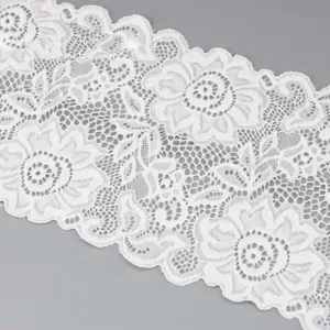 Detailopname van witte elastische kantstof borden met een prachtig bloemenmotief.