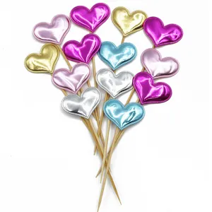Close-up detail of shiny PU heart cake toppers with wooden sticks for party decoration.