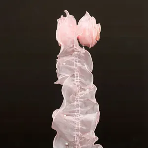 Vista detallada del borde de encaje plisado de organza rosa con perlas para costura y decoracion.