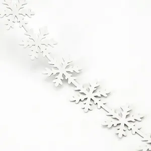 Close-up detail of white snowflake ribbon, delicate cutout holiday decoration trim for gift wrap.