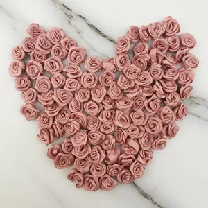 Detalle de mini rosas de cinta de satén en forma de corazón para manualidades y decor.
