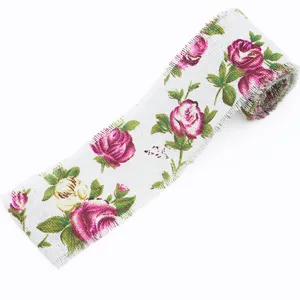 Close-up view of vintage pink rose printed white linen ribbon roll with delicate frayed edge detail.