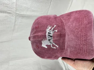Detailed view of white floral horse embroidery on a washed burgundy cotton baseball cap.