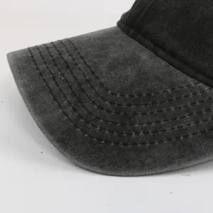 Close-up of washed black baseball cap brim with six rows of reinforced stitching details.
