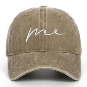 Detailed macro view of a khaki washed cotton baseball cap with white cursive me embroidery