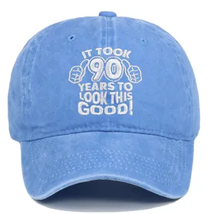 Detailed view of the '90 Years' embroidery on a blue distressed cotton baseball cap.