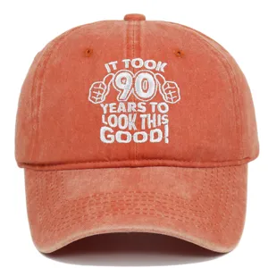 Close-up of "IT TOOK 90 YEARS TO LOOK THIS GOOD!" embroidery on an orange washed cotton cap.