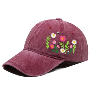 Detailansicht einer weinroten Baseballkappe mit feiner Blumen- und Bienenstickerei.