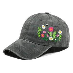 Nahaufnahme der floralen Stickerei auf einer grau gewaschenen Denim-Baseballkappe.
