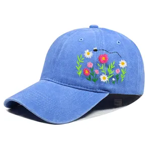 Detail der bunten Blumen- und Insektenstickerei auf der Seite einer blauen Kappe.