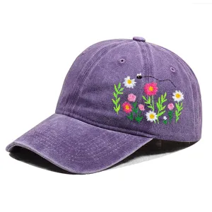 Detailaufnahme der Blumenstickerei und Biene auf einer lila Baumwoll-Baseballkappe.