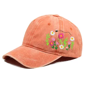 Detailansicht der Blumen- und Bienenstickerei auf einer orangefarbenen Baseballkappe aus Baumwolle