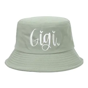 Close-up of white cursive 'Gigi' embroidery on a sage green cotton bucket hat