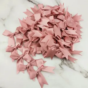Close-up detail of dusty pink satin ribbon bows, craft DIY wedding hair accessory decoration.