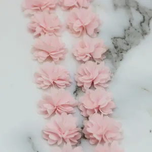 Close-up of pink chiffon flower lace trim, delicate fabric sewing accessory detail view.