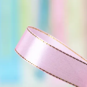 Close-up detail of 2.5cm pink satin ribbon with metallic gold edge for gift wrapping.