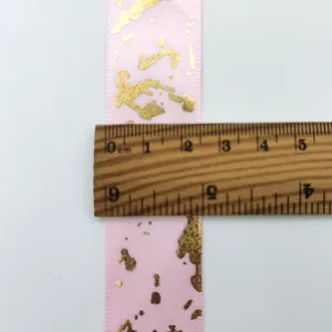 Dettaglio nastro di raso marmo rosa e foglia d'oro che mostra misurazione larghezza 2.5cm.